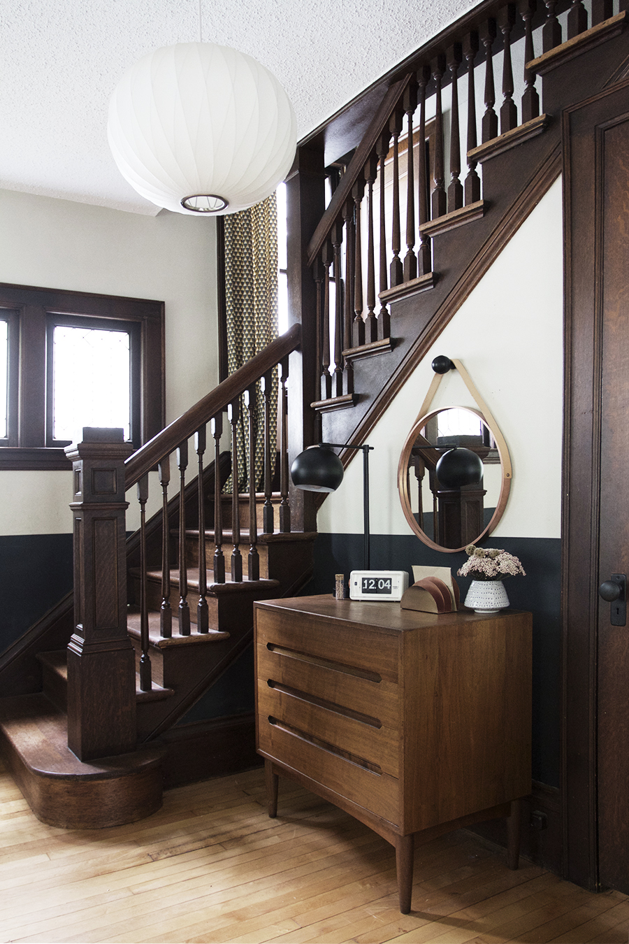 Simple Entryway with round mirror and midcentury dresser